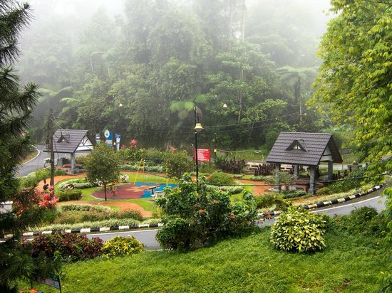 Misty playground and garden area in Fraser's Hill surrounded by lush greenery and small pavilions.