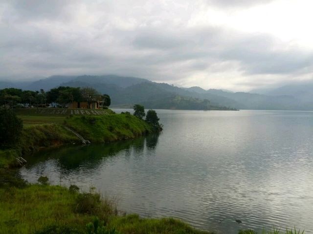 Scenic view and overlooking a calm reservoir surrounded by misty mountains